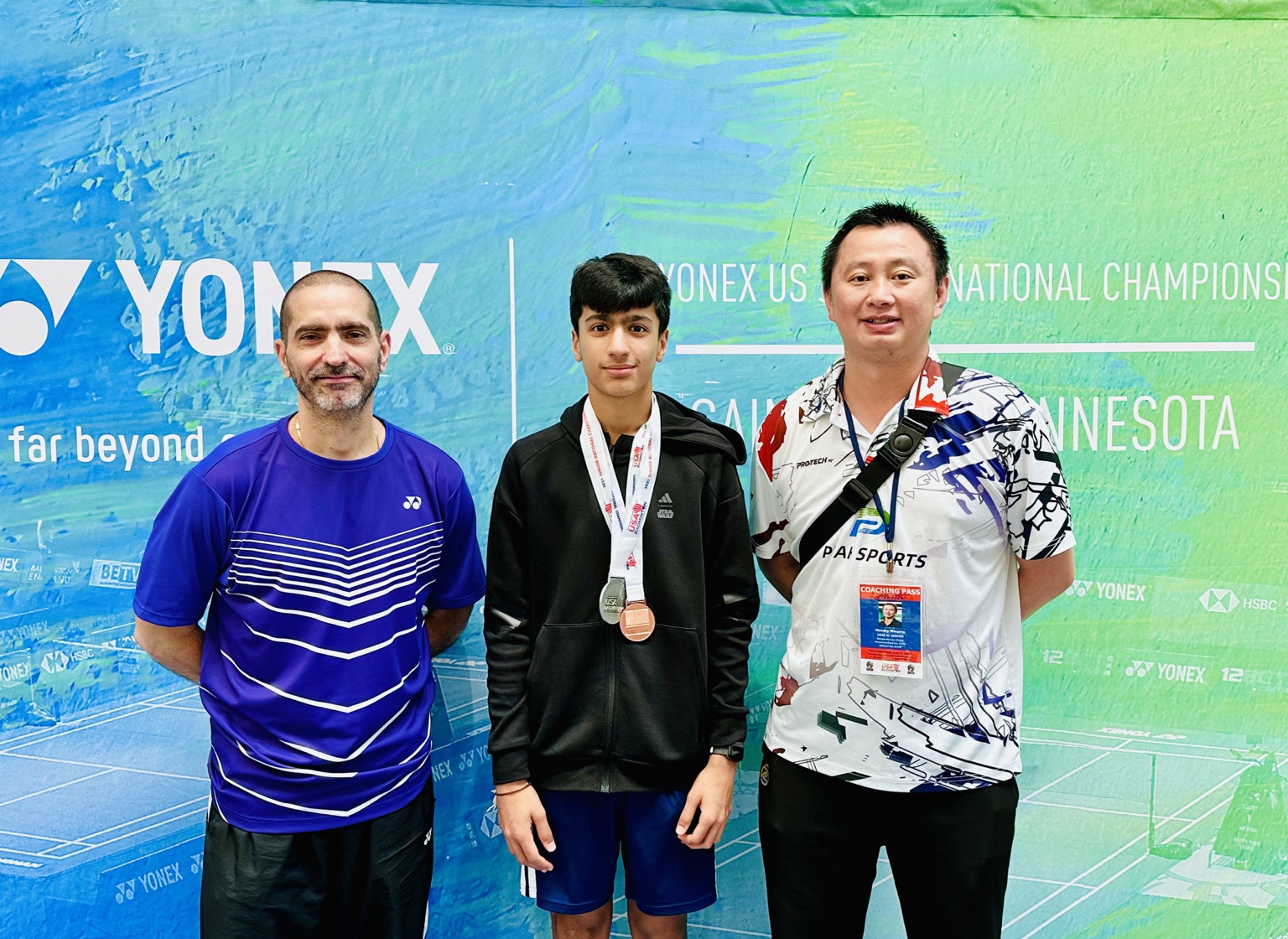 Aarav wearing his Junior Nationals medals with two coaches